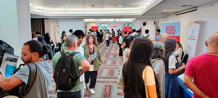 Pasillo donde se realiza el evento. Varias personas caminando. 